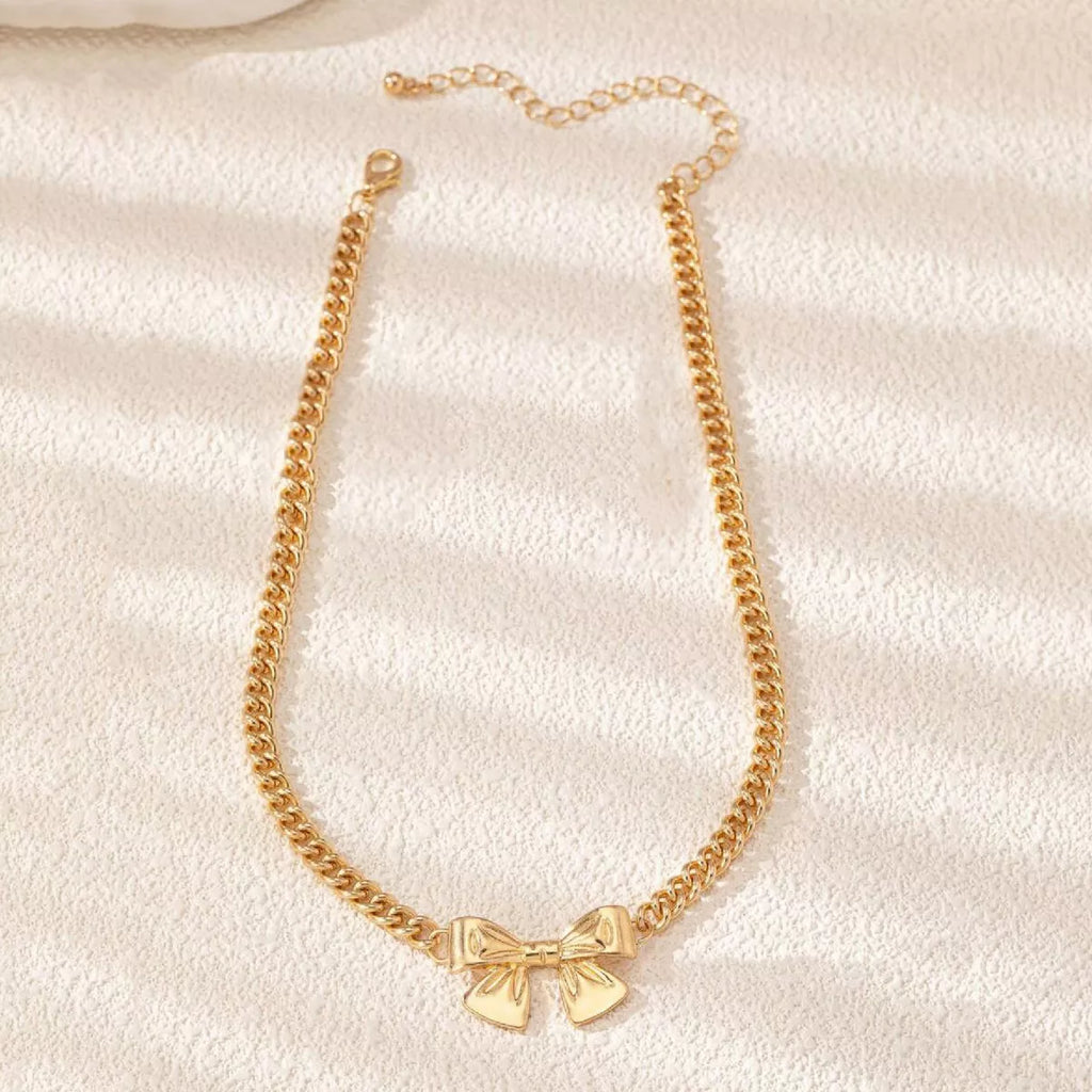 Flatlay view of 18K gold-plated bowknot necklace showing full chain layout and lobster clasp.