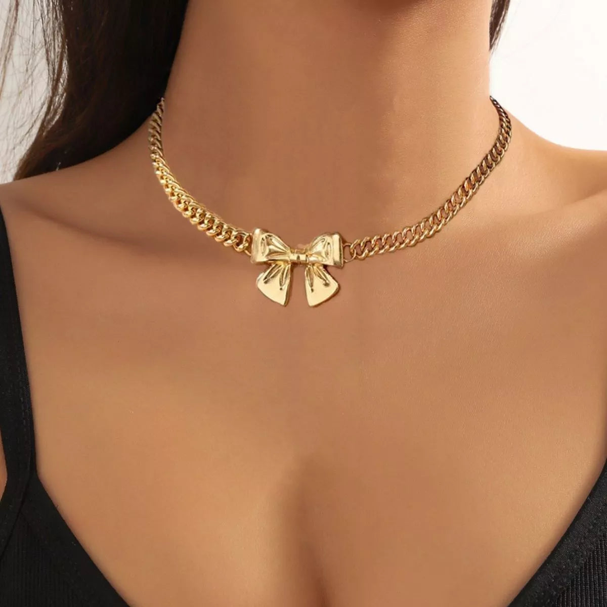 Model wearing an 18K gold-plated bowknot pendant necklace with a Cuban link chain.
