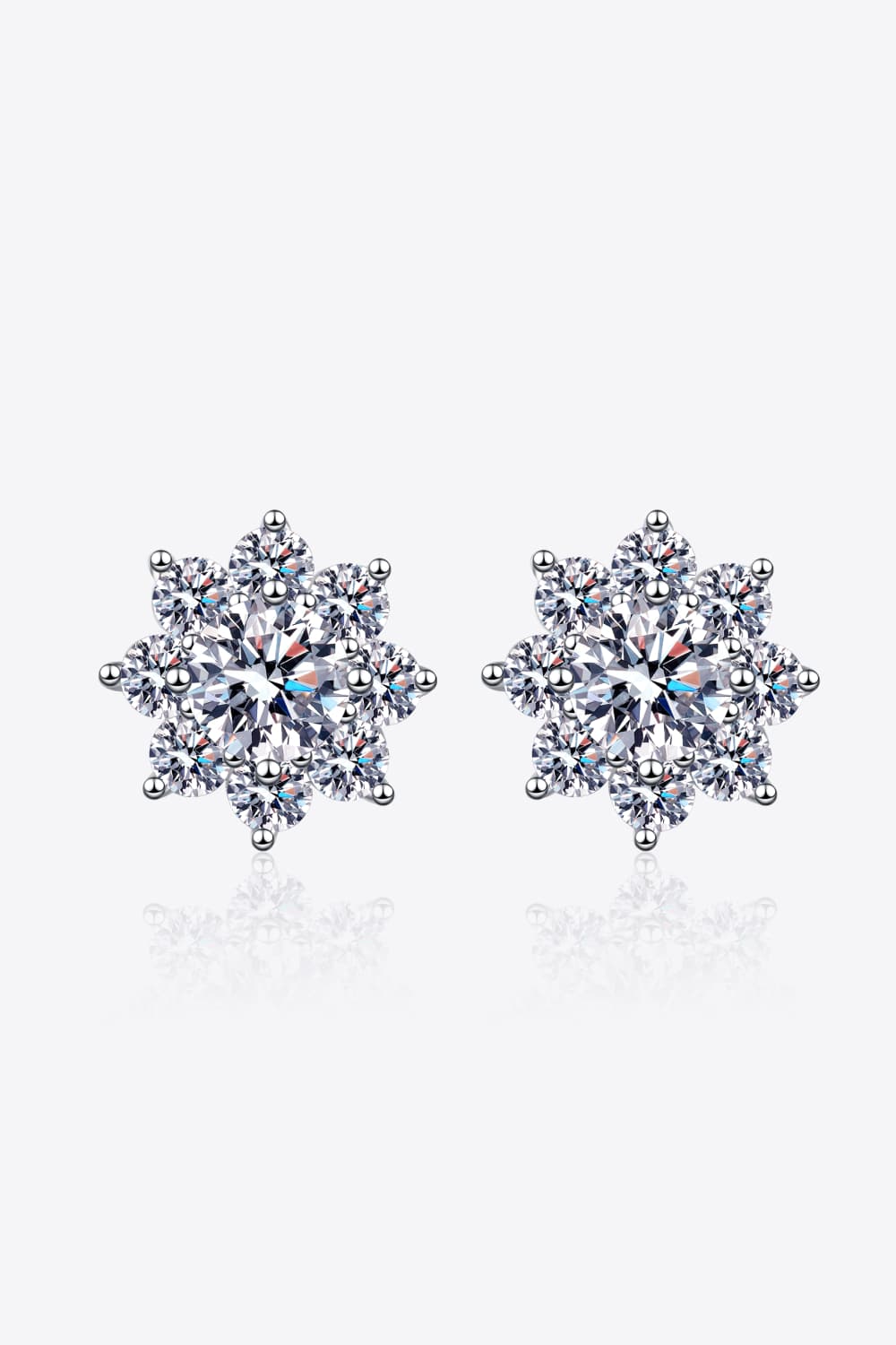 1 carat moissanite flower stud earrings in 925 sterling silver on white reflection surface.