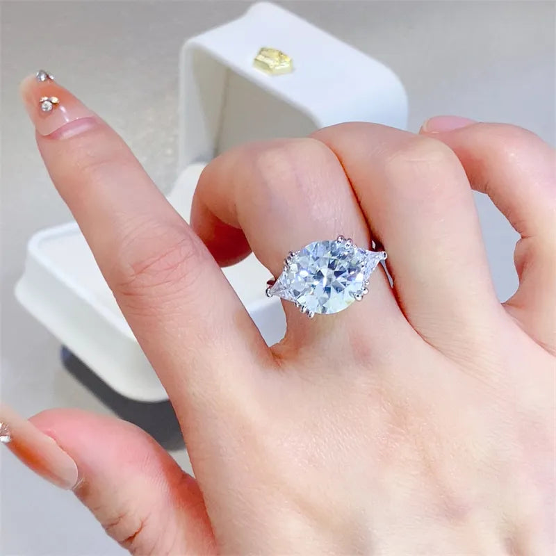 Woman wearing 5 carat round moissanite ring with side stones in 925 sterling silver.