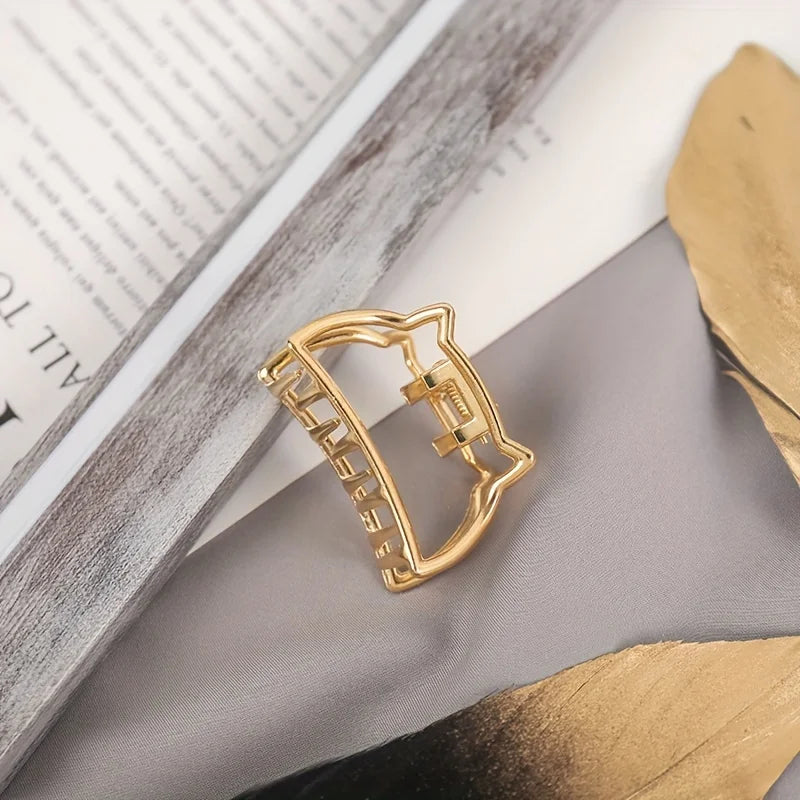 Geometric Hollow Hair Claw Clip in gold-tone metal finish, in hand for scale - Varex HQ