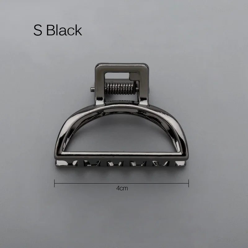 Geometric Metal Hair Claw Clip in silver, black and gold-tone metal finish, in hand for scale - Varex HQ