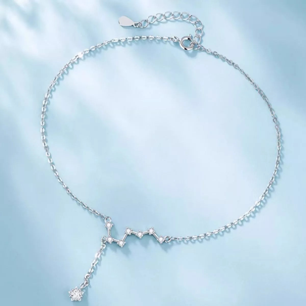Full view of Glintstar zircon constellation anklet on blue silk, Varex HQ
