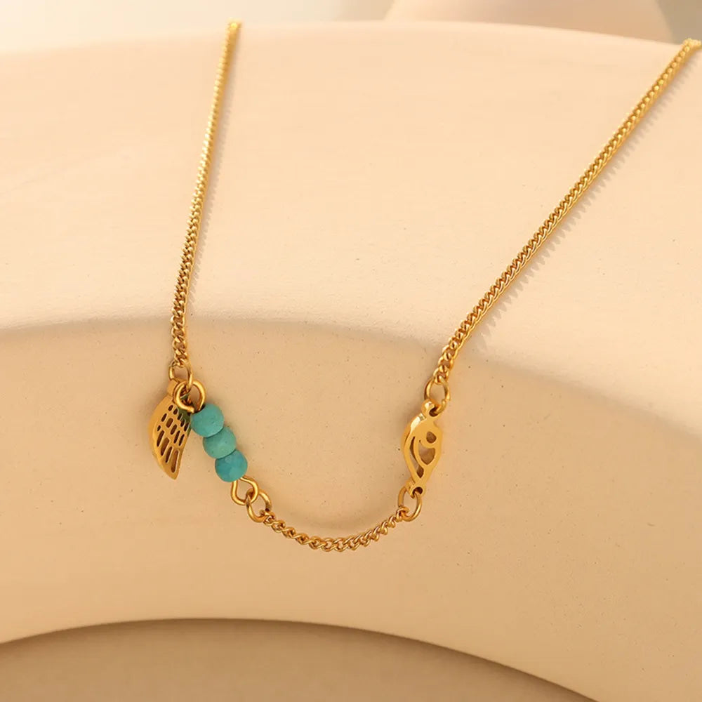 Close-up details of gold feather wing charm and turquoise beads on titanium steel chain