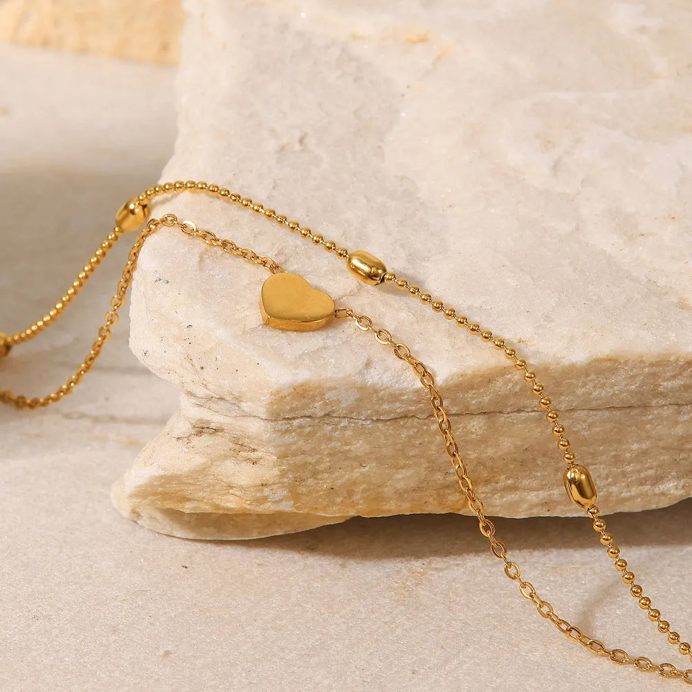Close up view of polished gold-plated heart charm and beaded chain