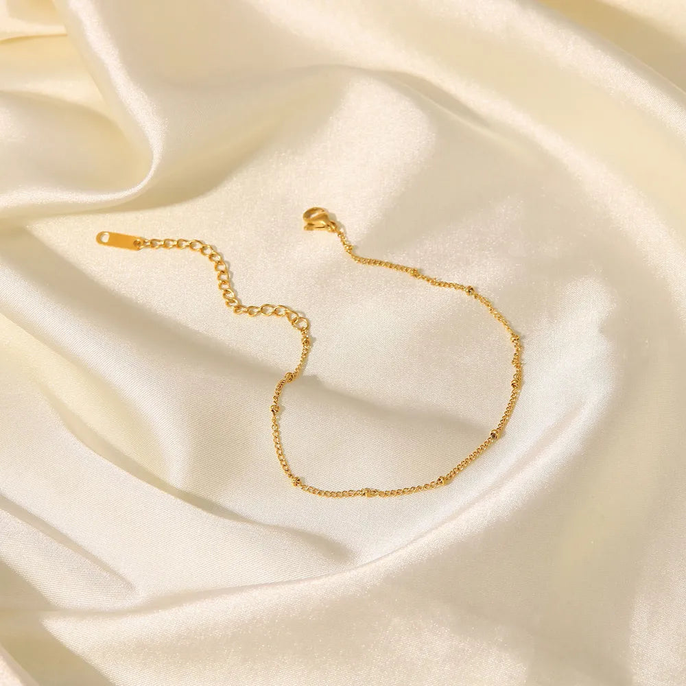 Elegant gold-plated bead chain draped over white satin silk