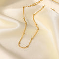 Gold-plated bead chain anklet on smooth white silk fabric