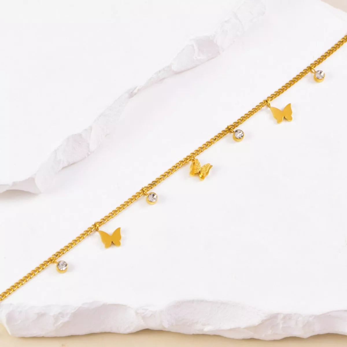 Close up details of gold-plated butterfly charms and bezel set zircon crystals