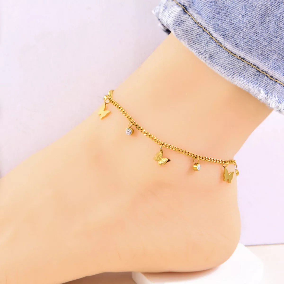 Woman wearing gold-plated butterfly charm anklet with zircon stones