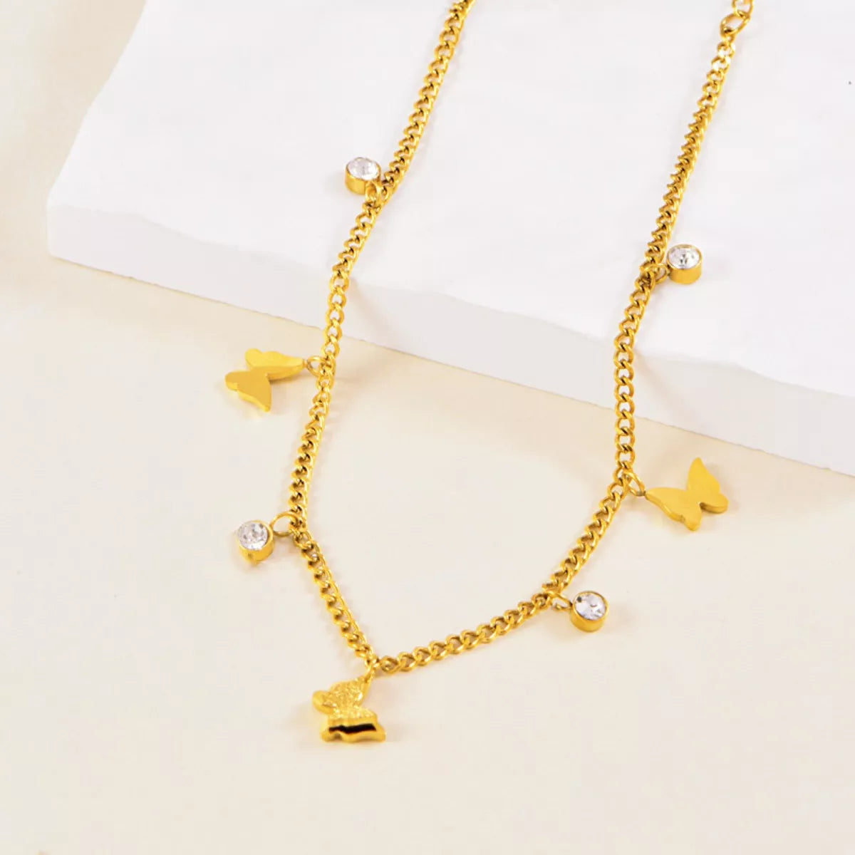 Gold-plated butterfly charm anklet with cubic zirconia on white stone