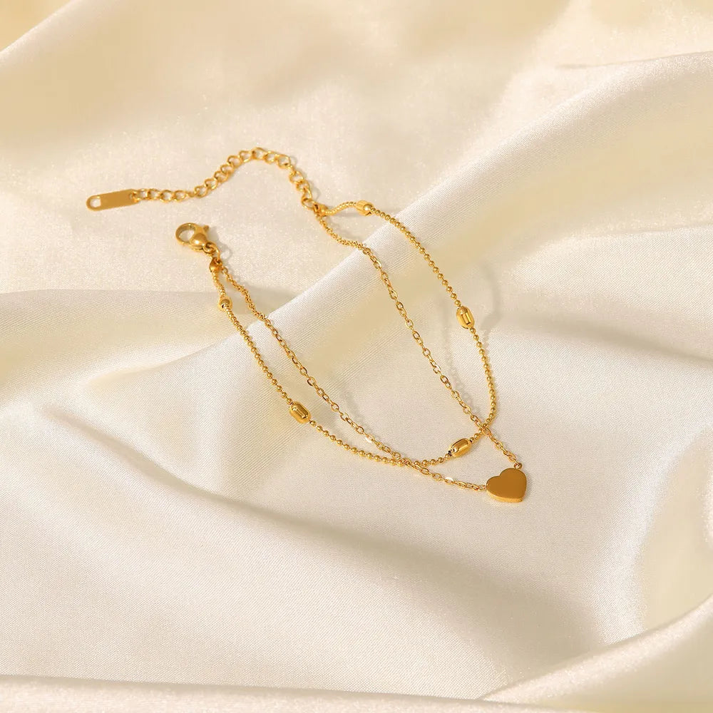Elegant gold-plated layered heart anklet on smooth white silk