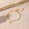 Double layered gold-plated heart anklet displayed on neutral stone background