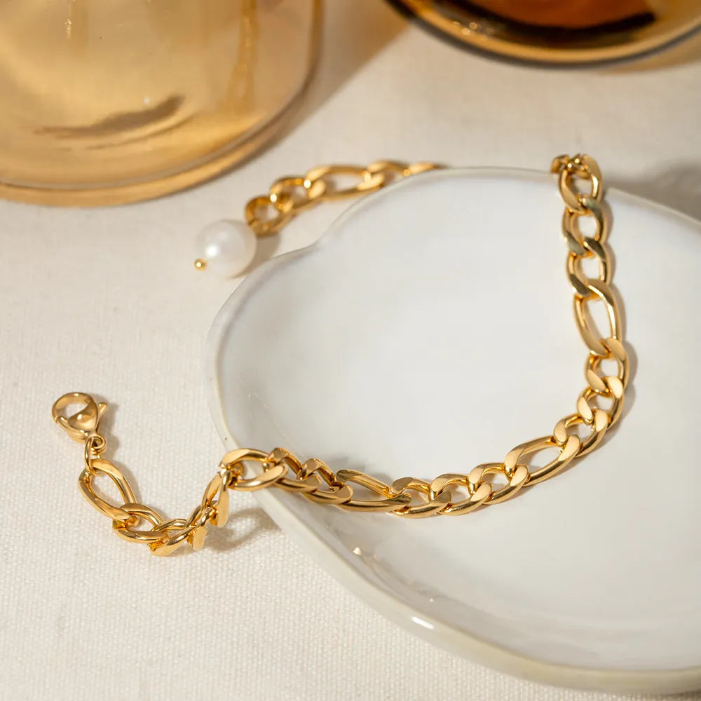 Gold-plated pearl chain anklet displayed on white ceramic dish