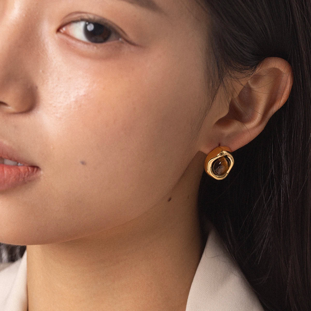 Gold-plated stud earrings with stone and faux-pearl accent, worn on model, close-up - Varex HQ