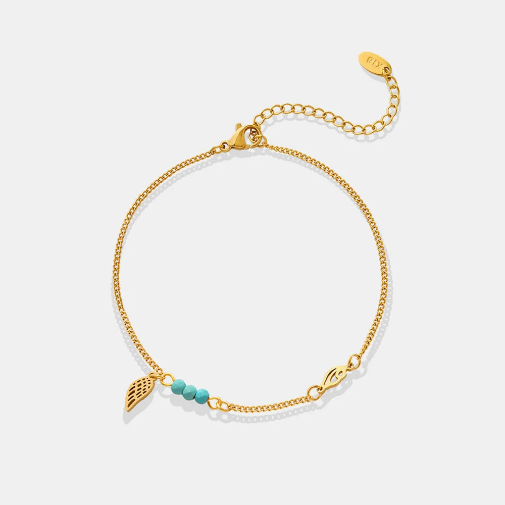 Gold-plated titanium steel anklet with wing charm and turquoise beads on plain white background