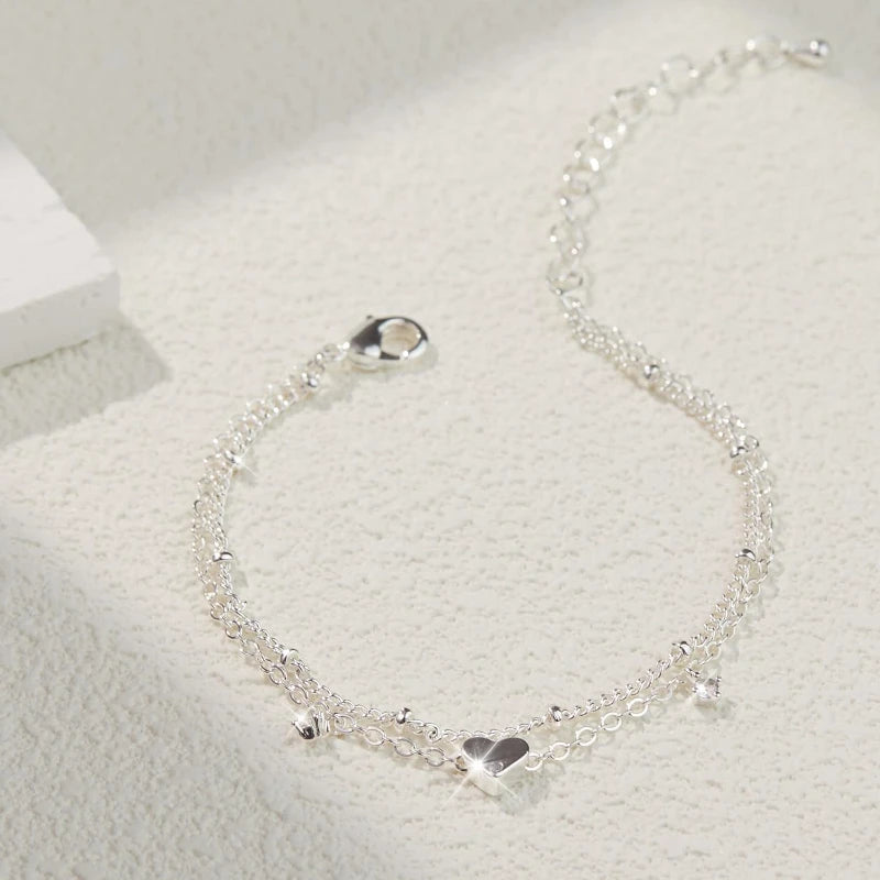 Silver-tone heart charm layered anklet, styled lifestyle shot, Varex HQ