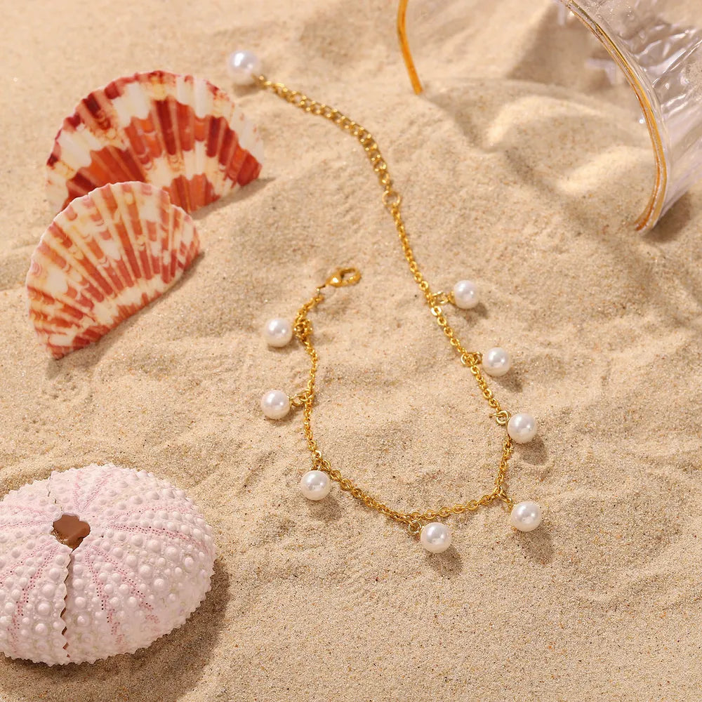 Lumina gold pearl charm anklet artfully styled on white beach sand with natural seashells and coral - Varex HQ summer collection
