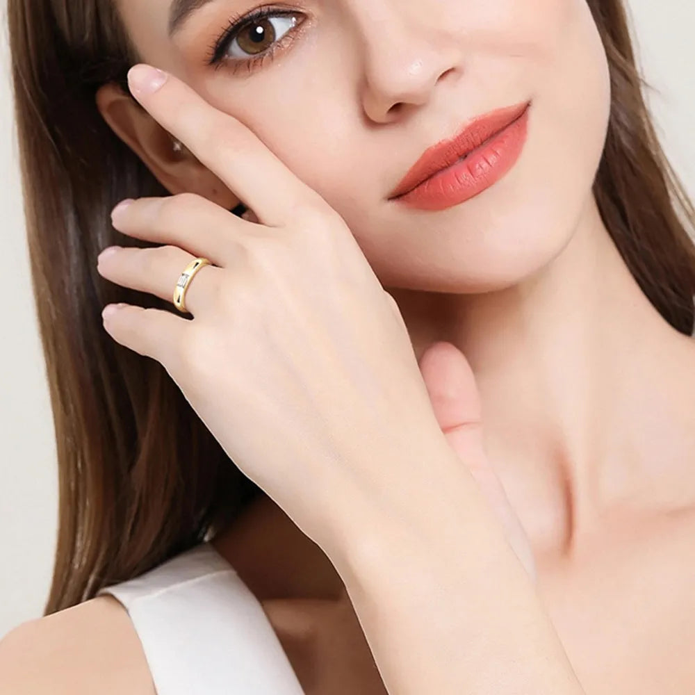 Woman wearing minimalist silver moissanite ring on finger close-up shot.