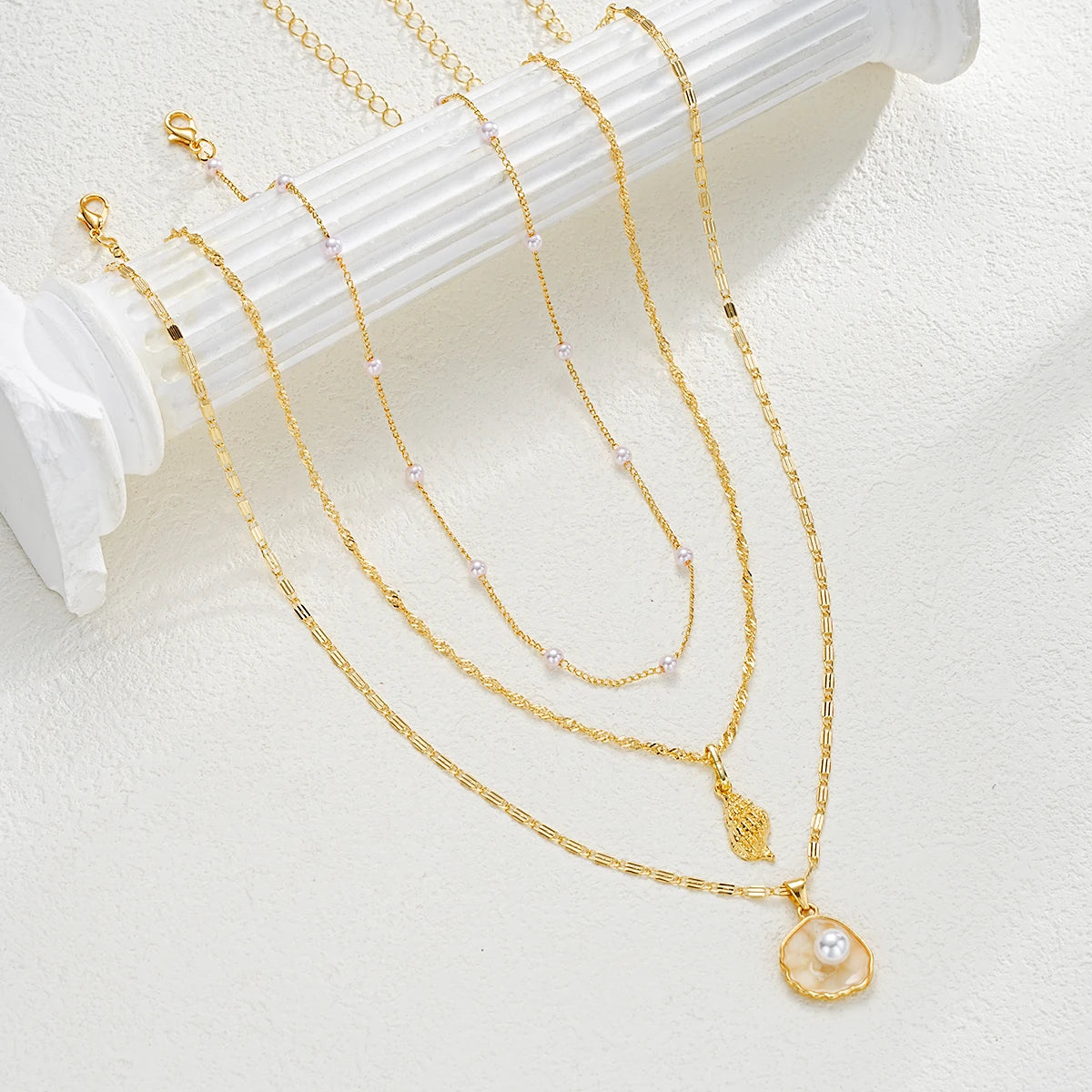 4-piece ocean charm layered necklace set in gold tones with shell, starfish, and pearl charms - pendant close-up - Varex HQ