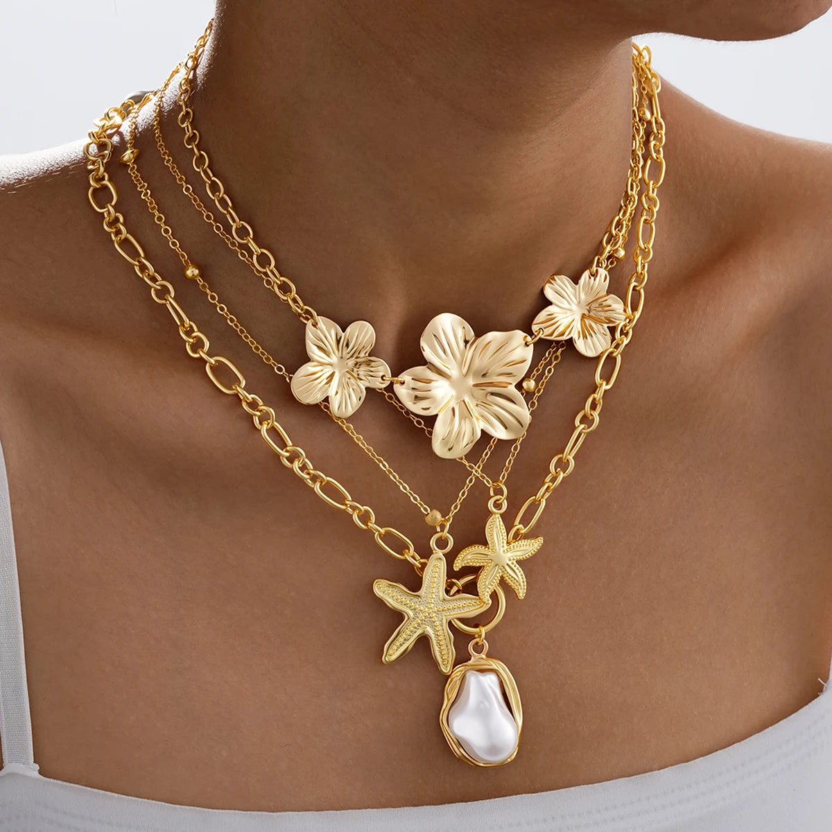 4-piece ocean charm layered necklace set in gold tones with shell, starfish, and pearl charms - side angle - Varex HQ