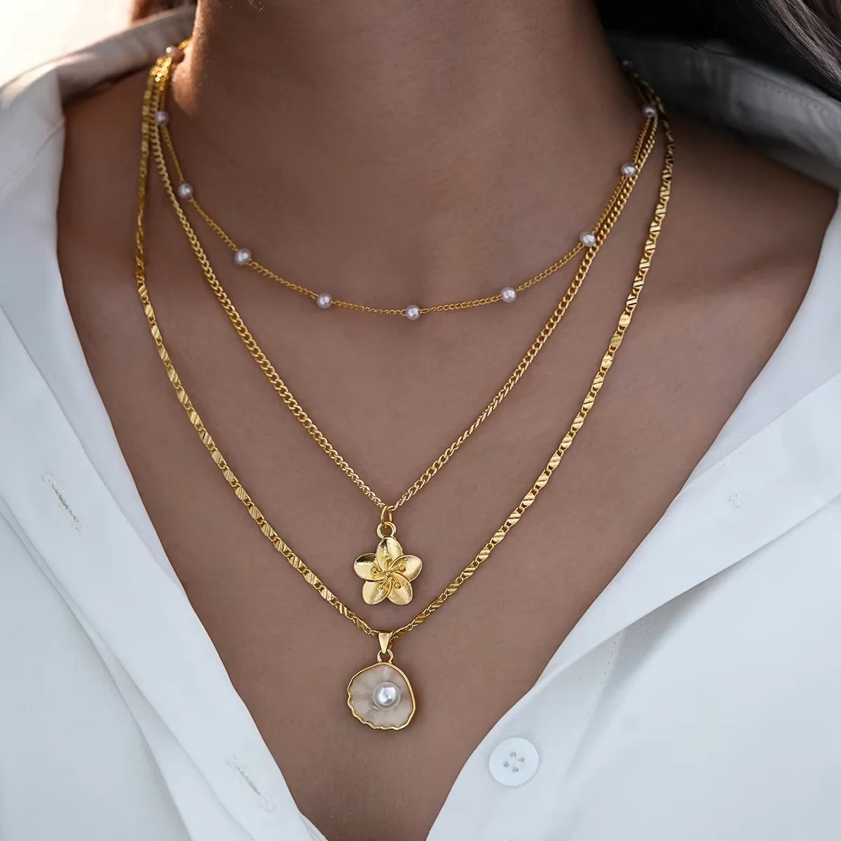 4-piece ocean charm layered necklace set in gold tones with shell, starfish, and pearl charms - on-model detail - Varex HQ