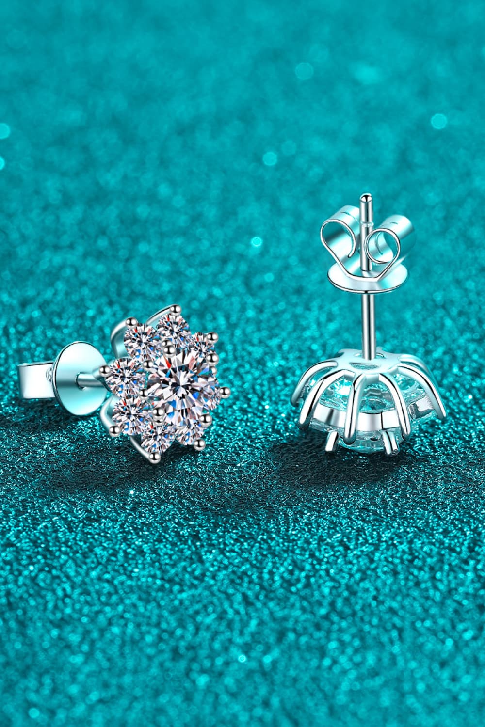 Angled view of rhodium-plated 925 sterling silver moissanite flower stud earrings showing post backings.
