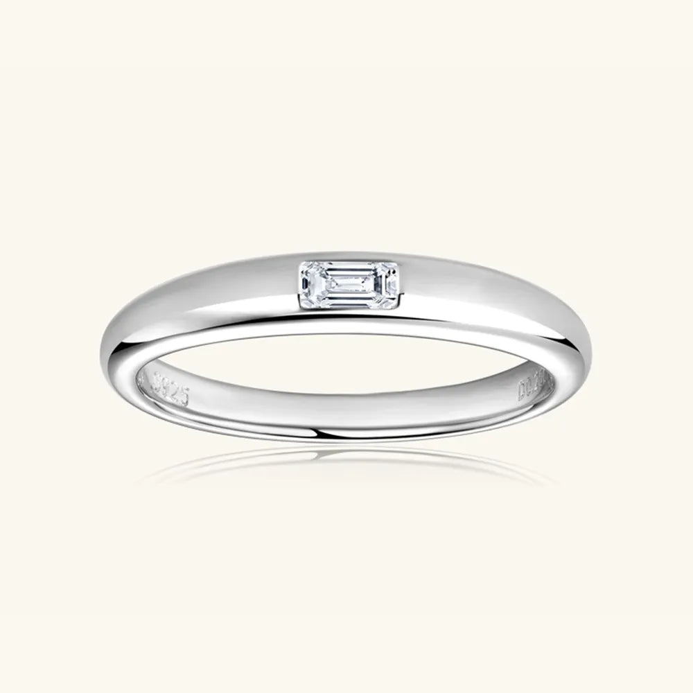 Studio shot of silver band ring featuring a flush-set oval moissanite gem.