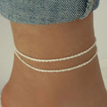 Silver-tone double layer sparkle anklet worn on ankle with denim jeans background