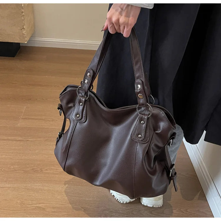 Vertical-Zip Vegan Leather Multi-Compartment Tote in coffee brown, held by hand showing front angle and buckle strap detail – Varex HQ