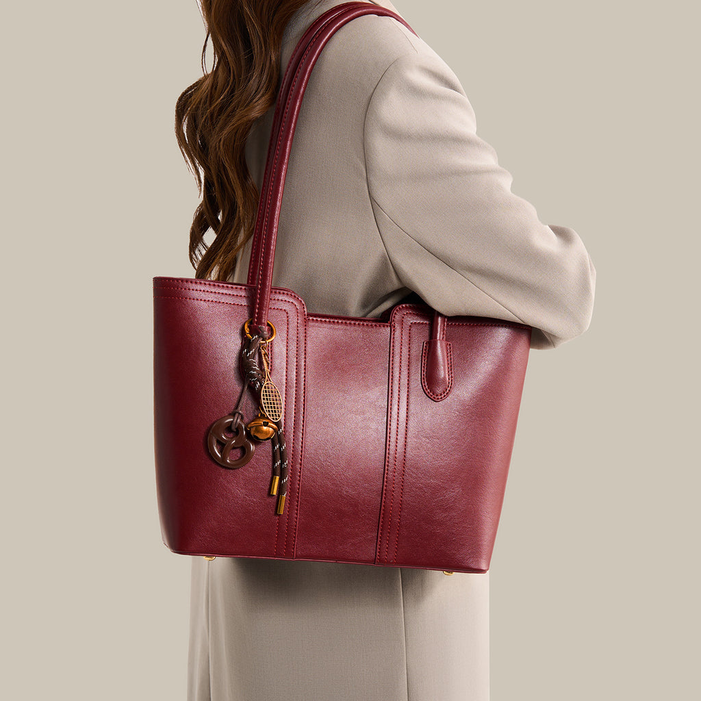 Wine red vegan leather tote bag - close-up of dual top handles and tassel charm hardware