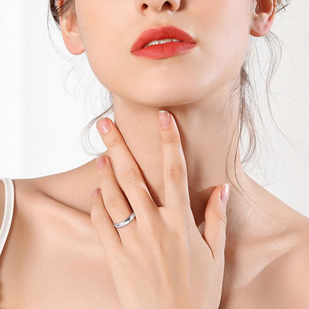 Portrait of woman wearing minimalist silver moissanite ring on pinky finger.