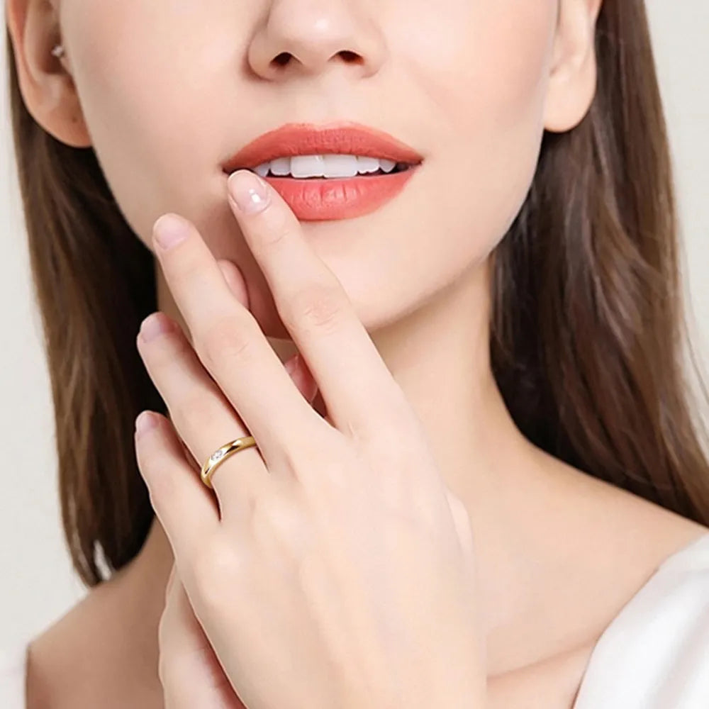 Close-up of woman displaying minimalist silver moissanite ring on her hand.